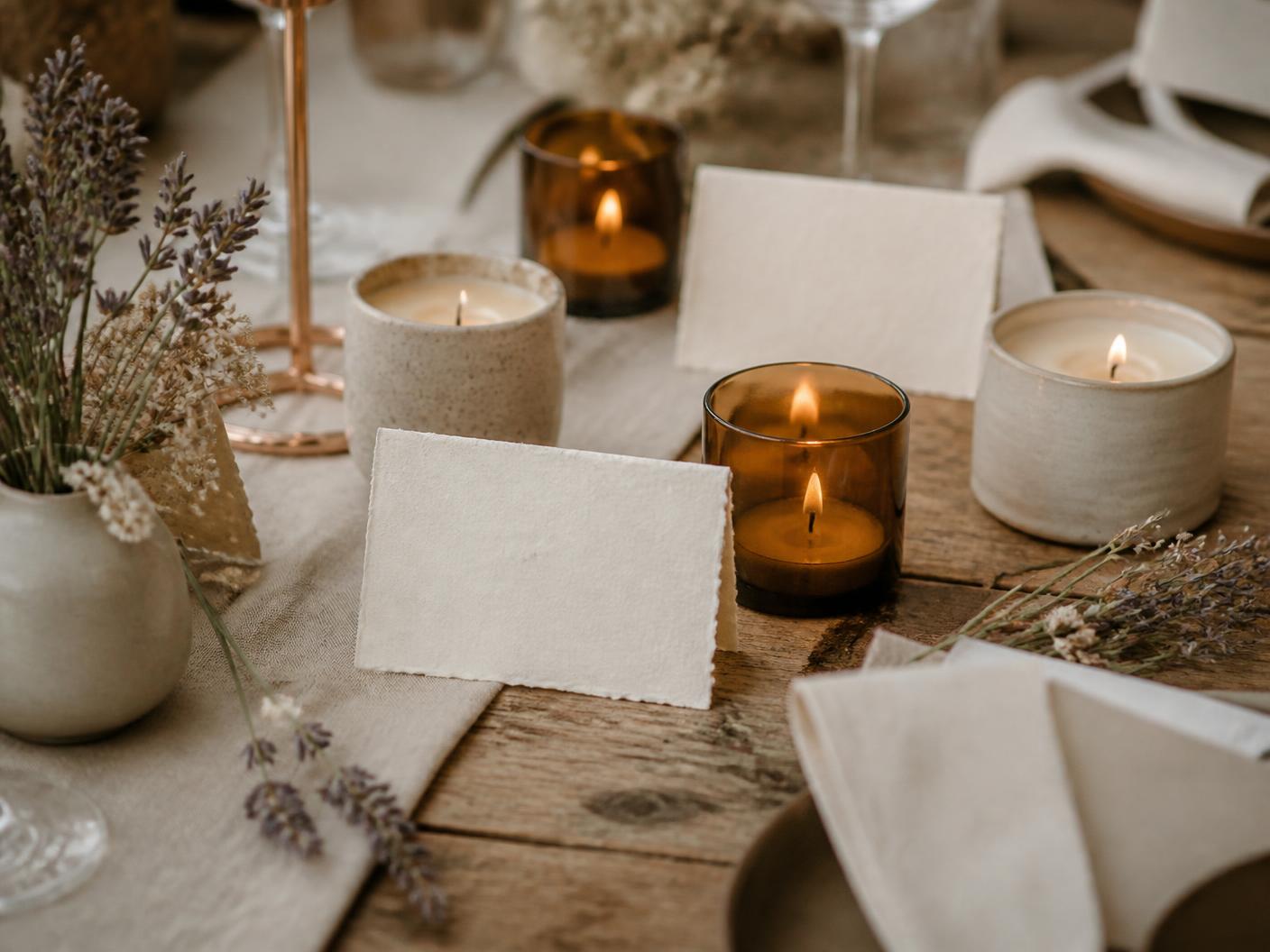 Mesa de celebração com velas artesanais em vidro âmbar e cerâmica, papel artesanal e flores secas